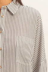 woman wearing a gray and white striped oversized shirt with a front pocket and button details