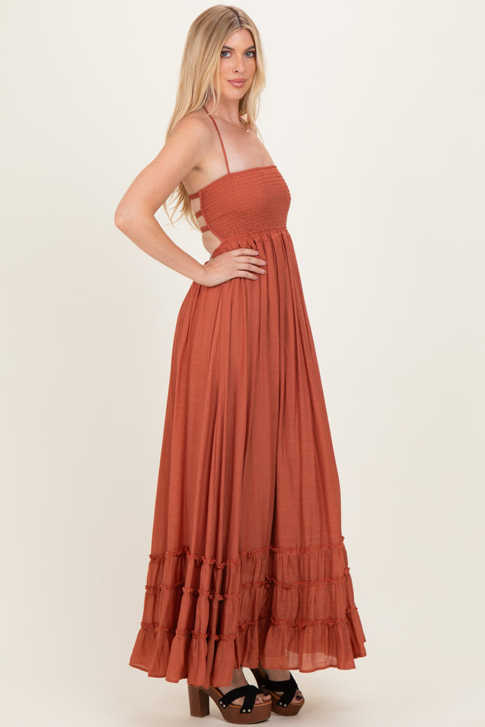 woman wearing an rust-colored maxi dress with a smocked bodice and tiered ruffle hem, styled with platform sandals