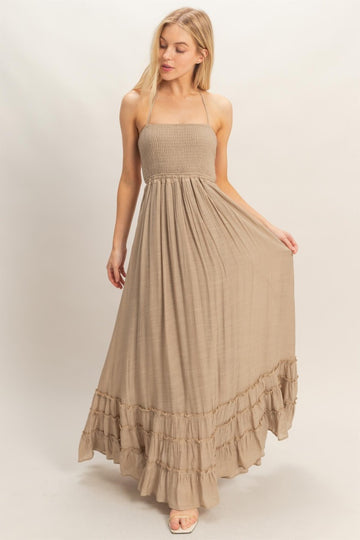 woman wearing a tan strapless maxi dress with a smocked bodice and ruffled hem