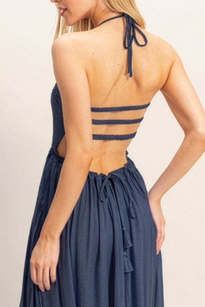woman wearing a navy blue halter neck dress with a smocked bodice and multiple back strap details