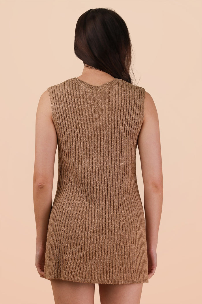 woman wearing a beige sleeveless ribbed knit dress, showing the back view against a light background