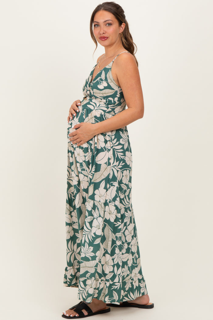 woman wearing a green floral maternity maxi dress and holding her baby bump