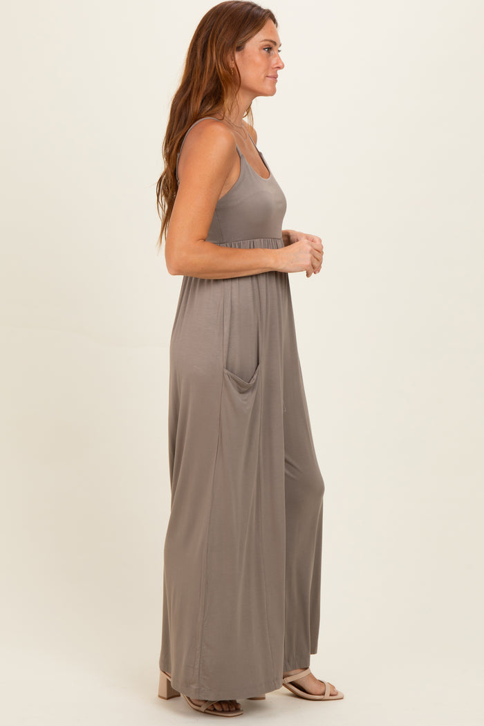 woman wearing a taupe long maxi dress with a fitted bodice and side pockets