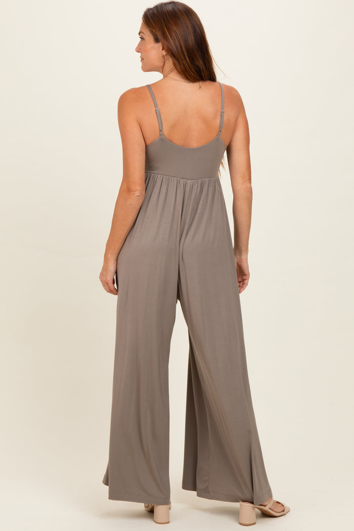 woman wearing a taupe sleeveless jumpsuit with a flowing wide-leg design, viewed from the back
