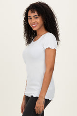 woman wearing a white ribbed top with scalloped sleeves and a fitted silhouette