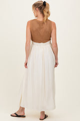woman wearing a sleeveless maternity maxi dress with a crochet top and flowy white skirt, showing her back