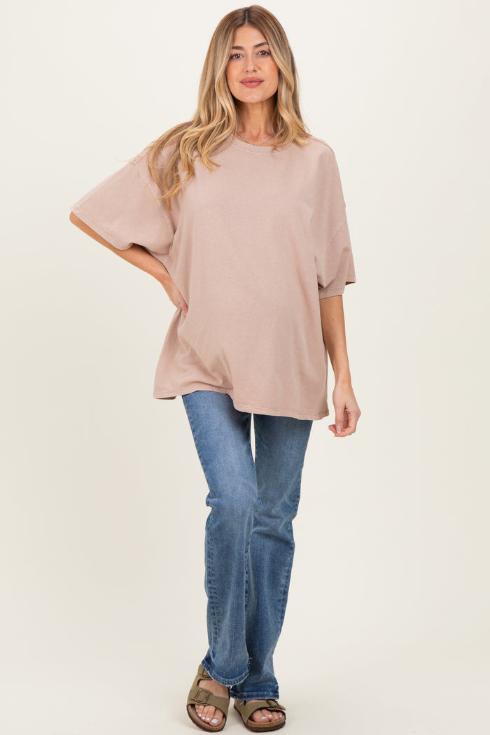 woman wearing a loose-fitting dusty pink maternity top with short sleeves and blue jeans