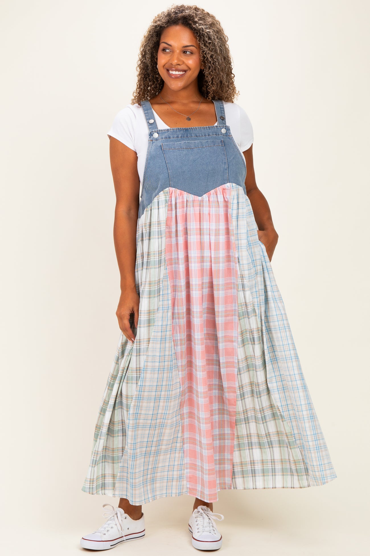 woman wearing a denim and plaid maxi dress with a fitted bodice and flowy skirt, styled casually with white sneakers