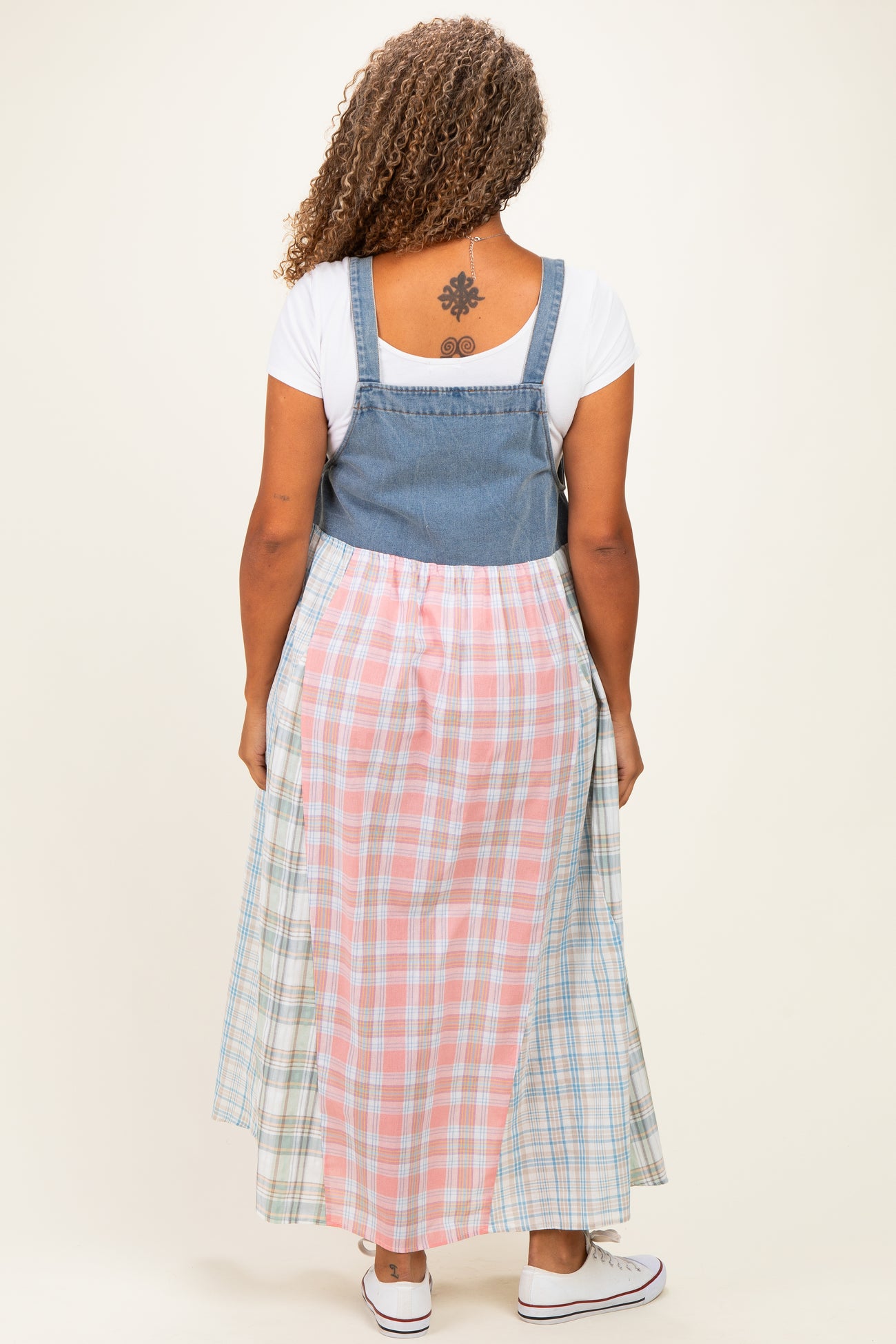 woman wearing a plus-size denim and plaid maxi dress with a fitted top and flowing skirt seen from the back