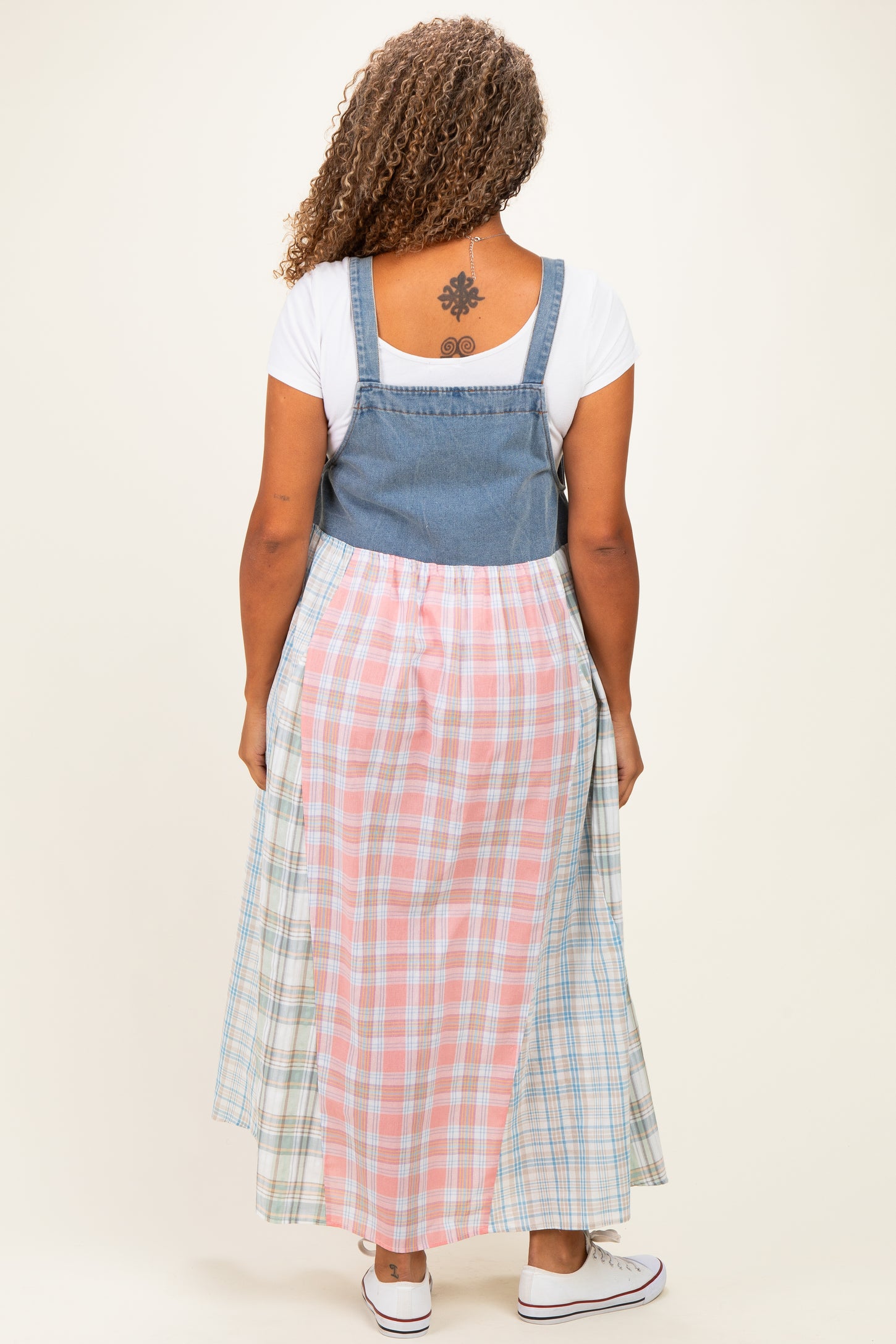 woman wearing a plus-size denim and plaid maxi dress with a fitted top and flowing skirt seen from the back