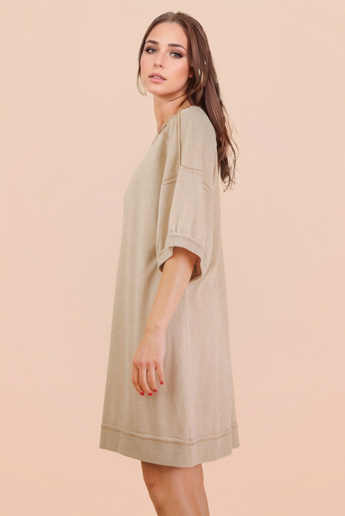 woman wearing a beige oversized t-shirt dress with short sleeves and a relaxed fit