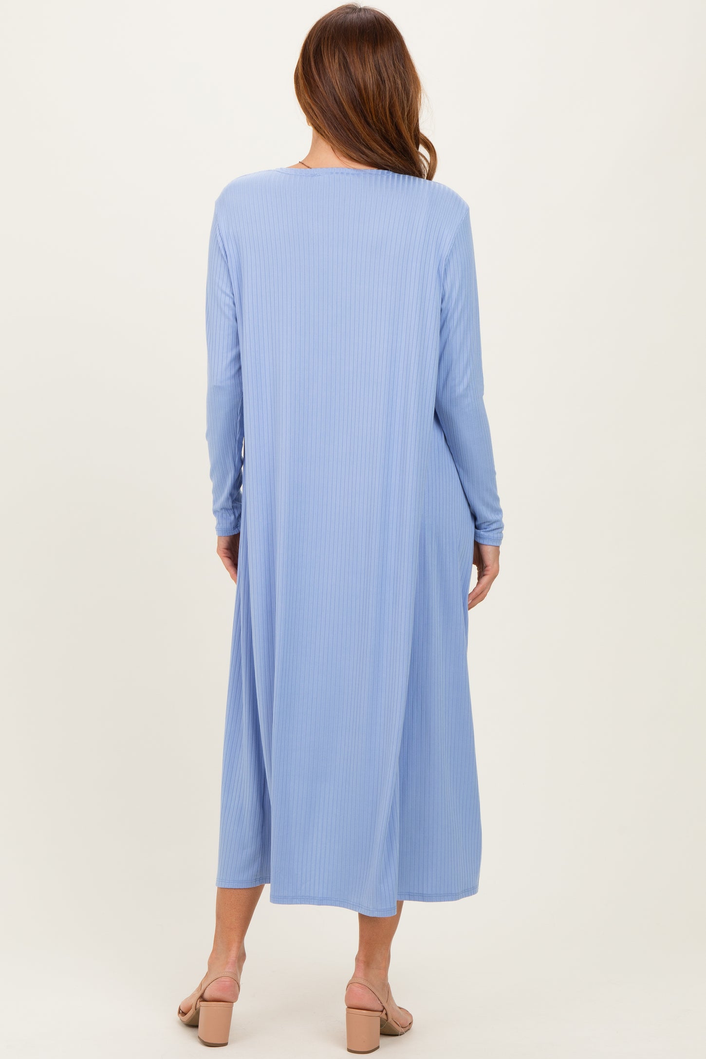 woman wearing a long sleeve blue ribbed maxi dress, viewed from the back, with a flowy silhouette and open back design