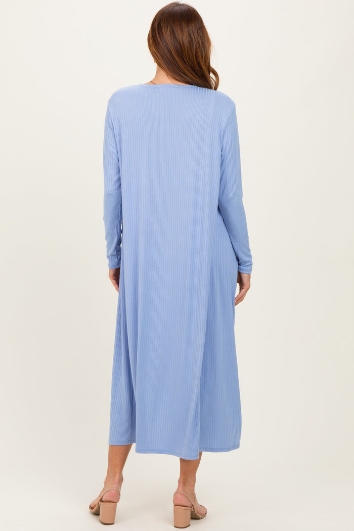 woman wearing a long sleeve blue ribbed maxi dress, viewed from the back, with a flowy silhouette and open back design