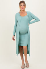 woman wearing a light teal maternity dress with a long matching cardigan and a visible baby bump