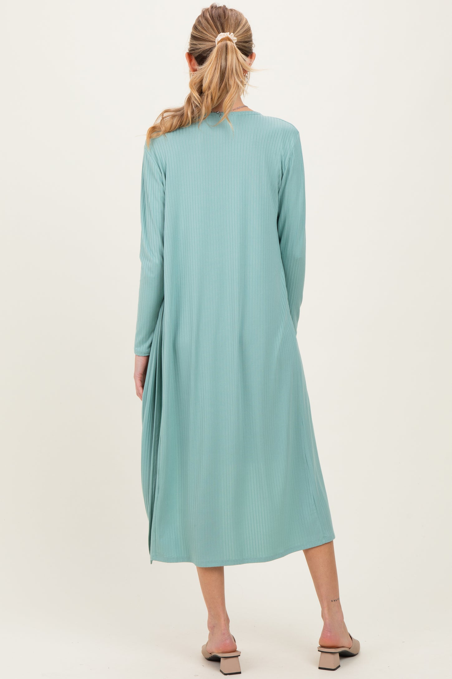 woman wearing a light green maternity duster with long sleeves and a flowy silhouette, viewed from the back