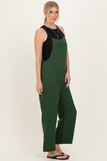 woman wearing a green sleeveless jumpsuit with wide legs and a black tank top underneath