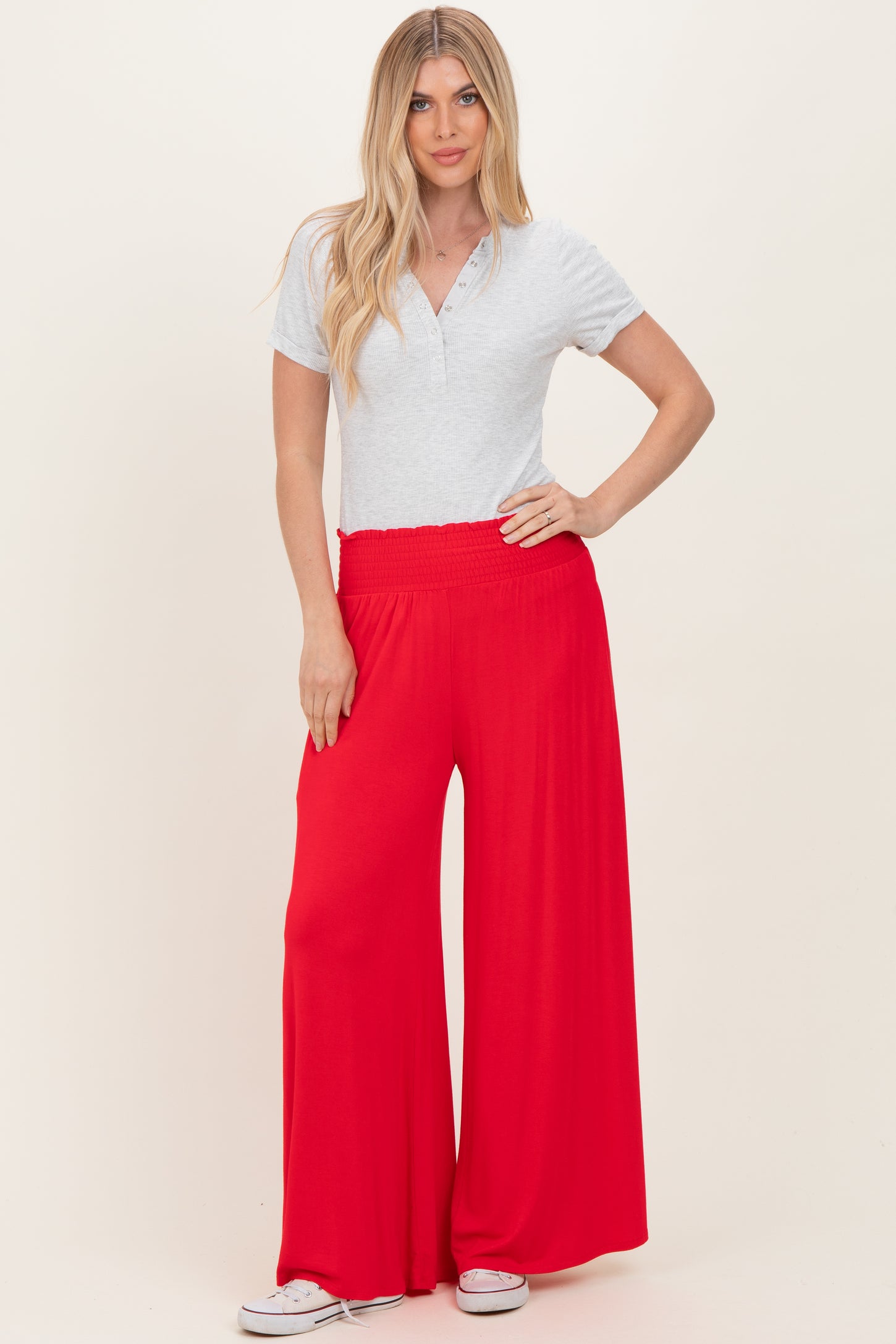 woman wearing a light grey short sleeve henley top and red wide leg pants with an elastic waistband