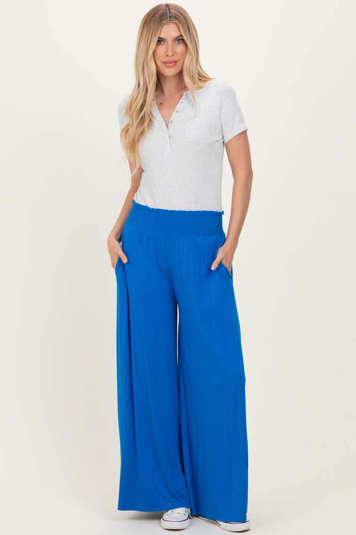 woman wearing a light gray short sleeve henley top and bright blue wide-leg pants with pockets