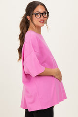 woman wearing a bright pink maternity oversized shirt with a baby bump visible