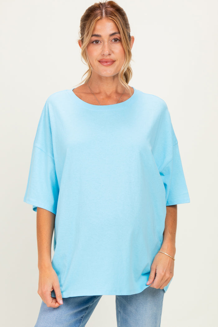 woman wearing a light blue oversized maternity top with short sleeves and a relaxed fit