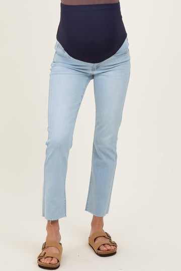 woman wearing light wash maternity jeans with a dark navy over-the-bump band and frayed hem