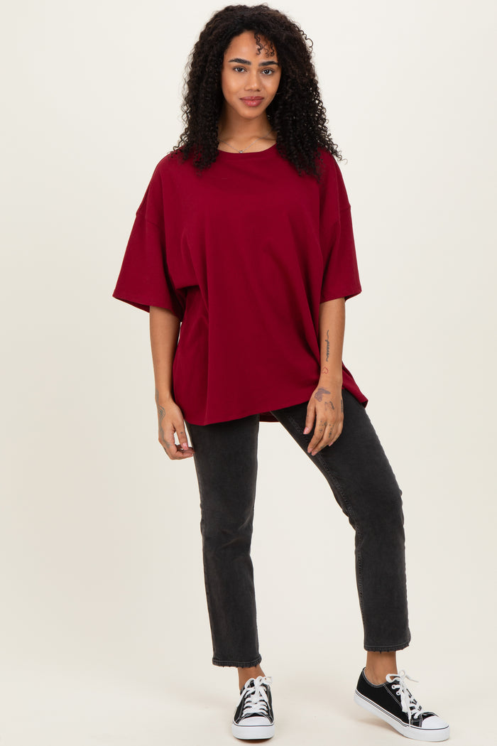 woman wearing a oversized burgundy t-shirt and black jeans, styled with black sneakers and curly hair