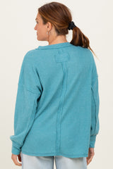 woman wearing a teal ribbed long sleeve top with a relaxed fit and back seam detail