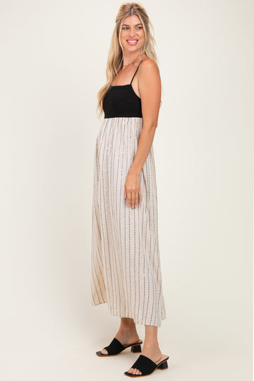 woman wearing a black and beige striped maxi dress with spaghetti straps and a flowy skirt