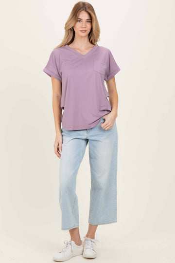 woman wearing a lavender short sleeve top with pocket and light blue wide leg jeans, standing casually
