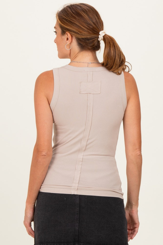 woman wearing a beige sleeveless top with a fitted silhouette and back detail