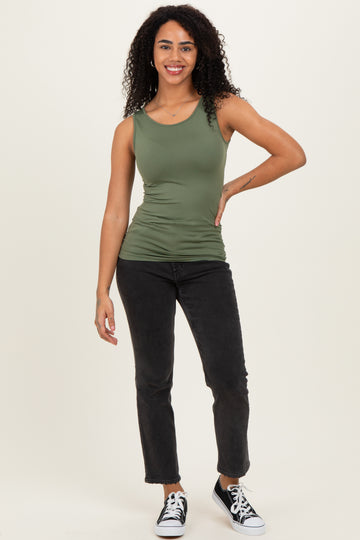 woman wearing a fitted olive green tank top and black cropped jeans with black sneakers