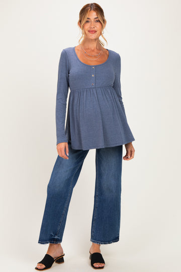 woman wearing a blue long sleeve maternity top with a button detail and a flowing fit paired with wide-leg jeans