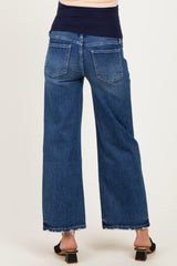 woman wearing dark blue wide leg maternity jeans with a frayed hem and a black top, showing her baby bump from the back