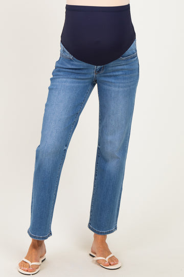 woman wearing a pair of blue maternity jeans with a navy belly panel and standing in sandals