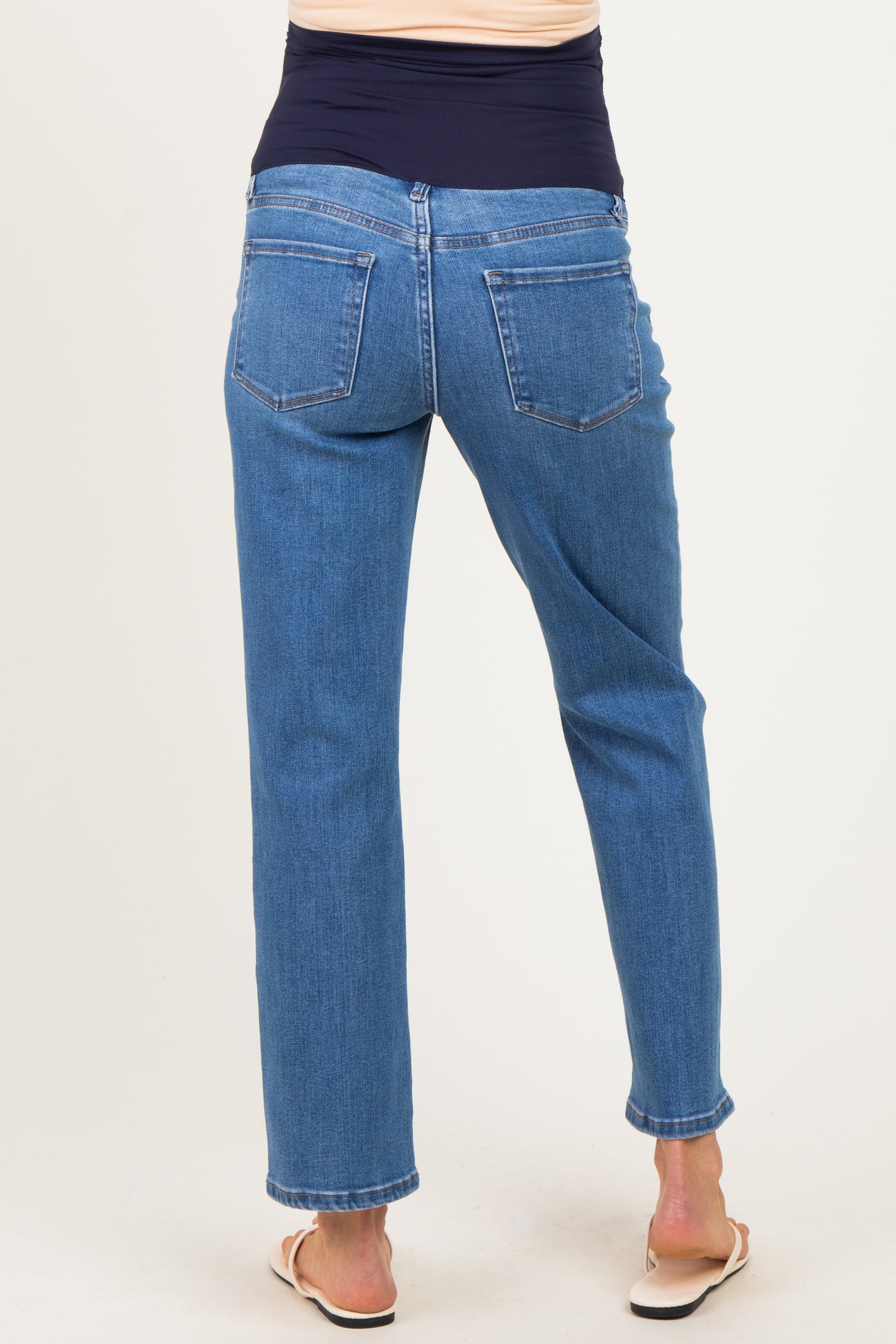 woman wearing a pair of medium wash maternity jeans with a fitted waistband, viewed from the back