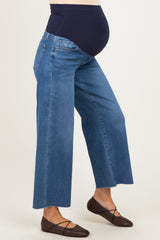 woman wearing maternity wide-leg jeans in medium wash with a supportive navy waistband and a visible baby bump