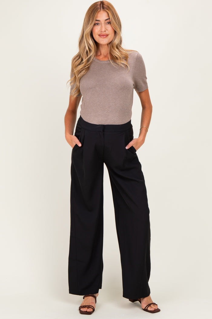 woman wearing a fitted brown short sleeve top and black wide leg maternity pants with pockets