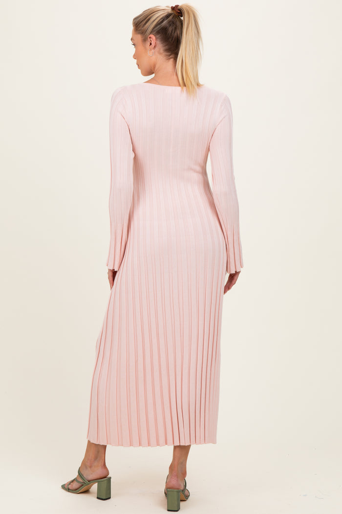 woman wearing a long pink ribbed maternity dress with long sleeves, viewed from the back