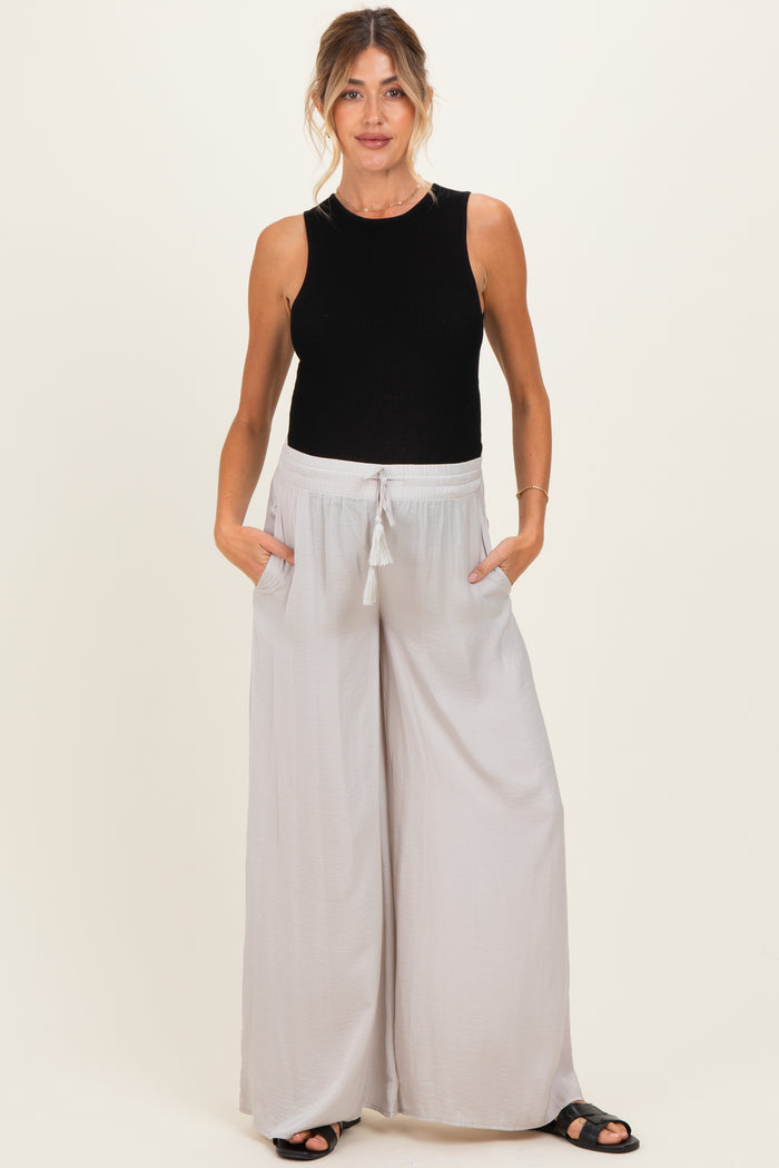 woman wearing a black ribbed maternity tank top and light grey wide-leg maternity pants with pockets and drawstring waist