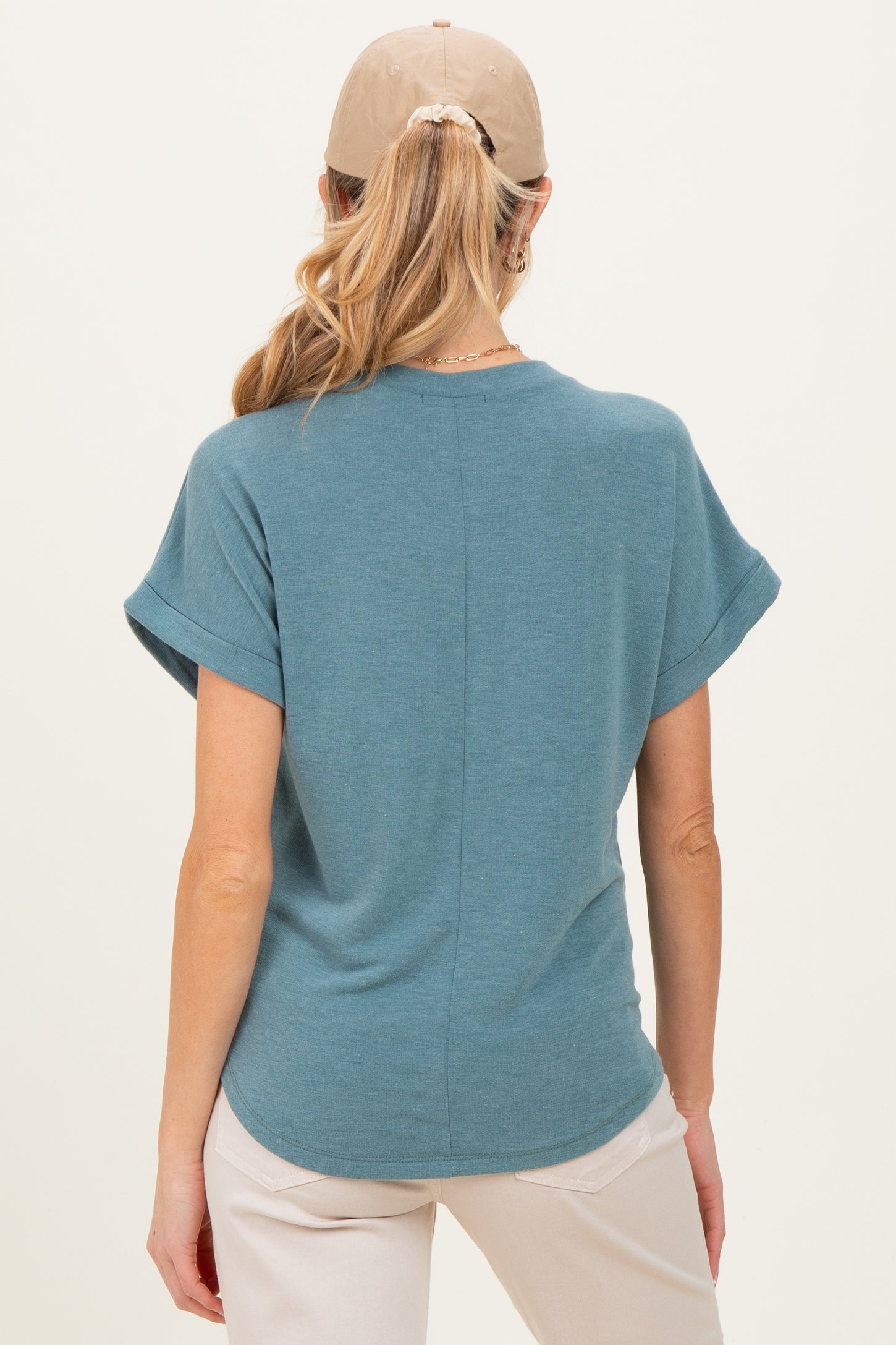 woman wearing a teal short sleeve maternity top, viewed from the back, with rolled sleeves and a relaxed fit