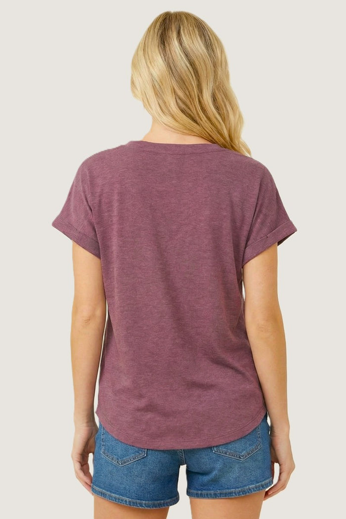 woman wearing a burgundy short sleeve tee with rolled cuffs and light blue denim shorts