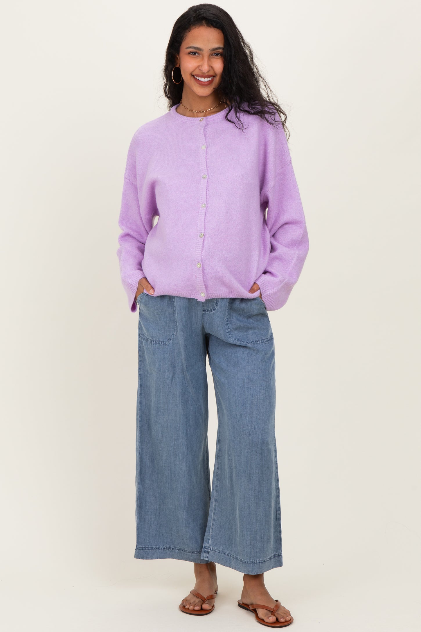 woman wearing a lilac maternity cardigan with buttons and relaxed blue wide-leg jeans