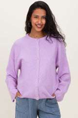 woman wearing a light purple maternity cardigan with buttons, smiling and posing with hands in pockets