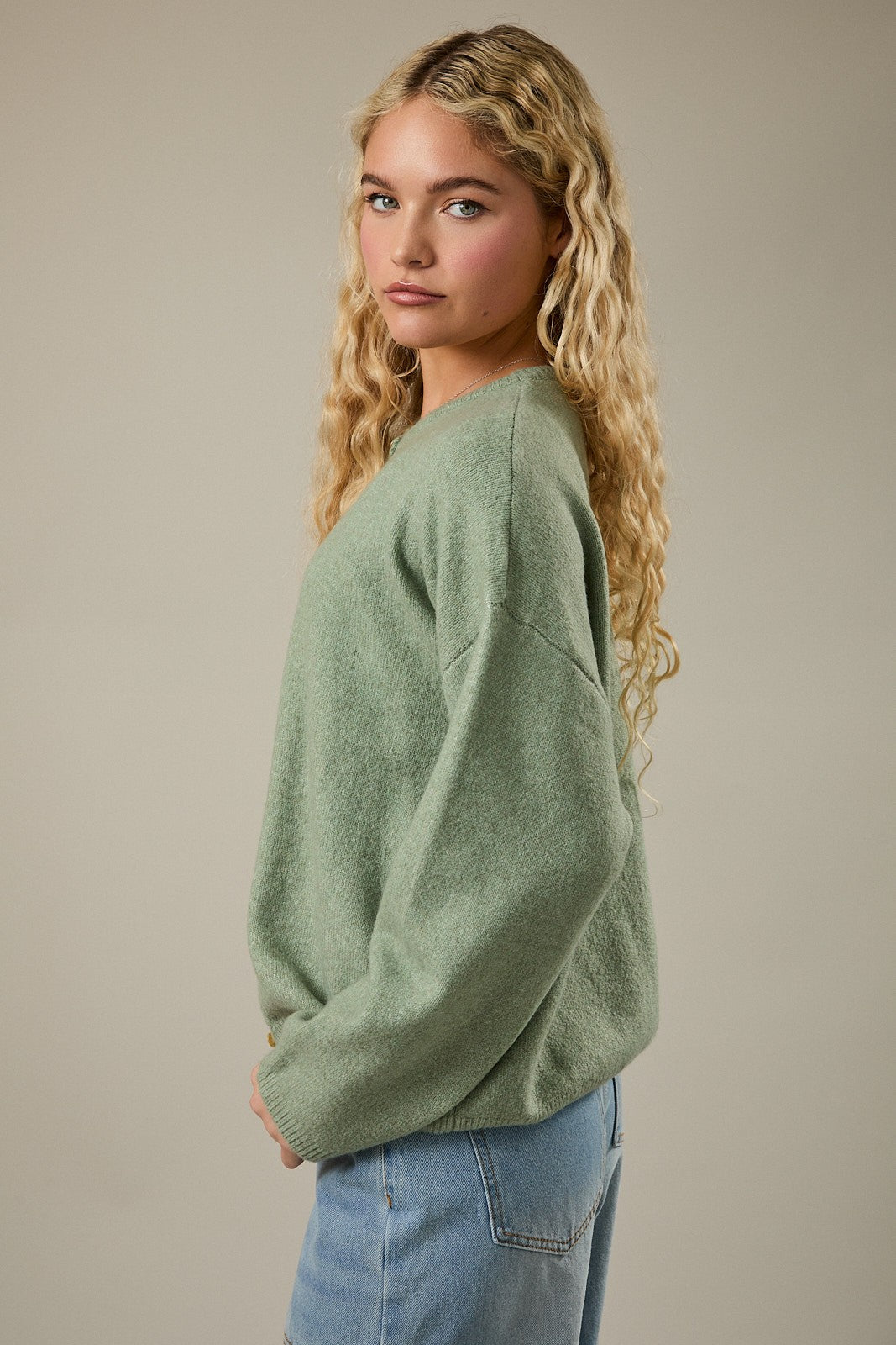 woman wearing a light green oversized sweater with a relaxed fit and curly hair styled down