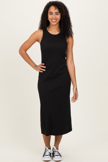 woman wearing a black sleeveless midi dress and black and white sneakers, standing with a smile