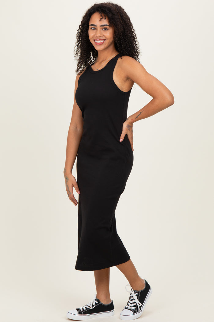 woman wearing a fitted black sleeveless midi dress and black sneakers, smiling and posing sideways