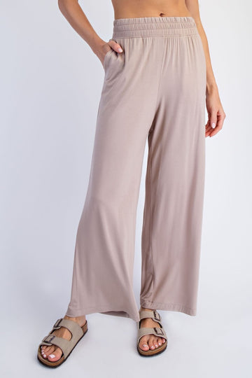 woman wearing beige wide-leg pants with an elastic waistband and side pockets, styled with casual sandals