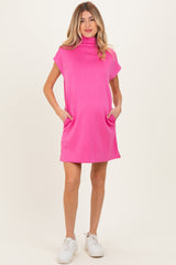 woman wearing a pink maternity dress with short sleeves and pockets, showcasing a baby bump