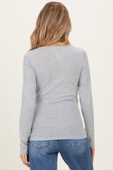 woman wearing a grey long sleeve maternity top from the back with blue jeans