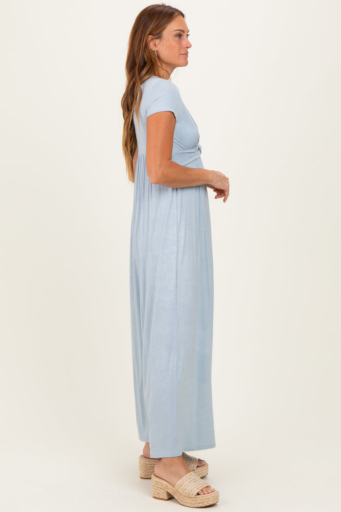 woman wearing a light blue short sleeve maxi dress with a knotted detail, standing sideways